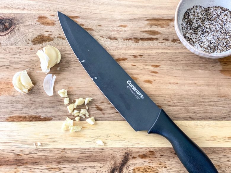 Smashed garlic on a wooden cutting board. 